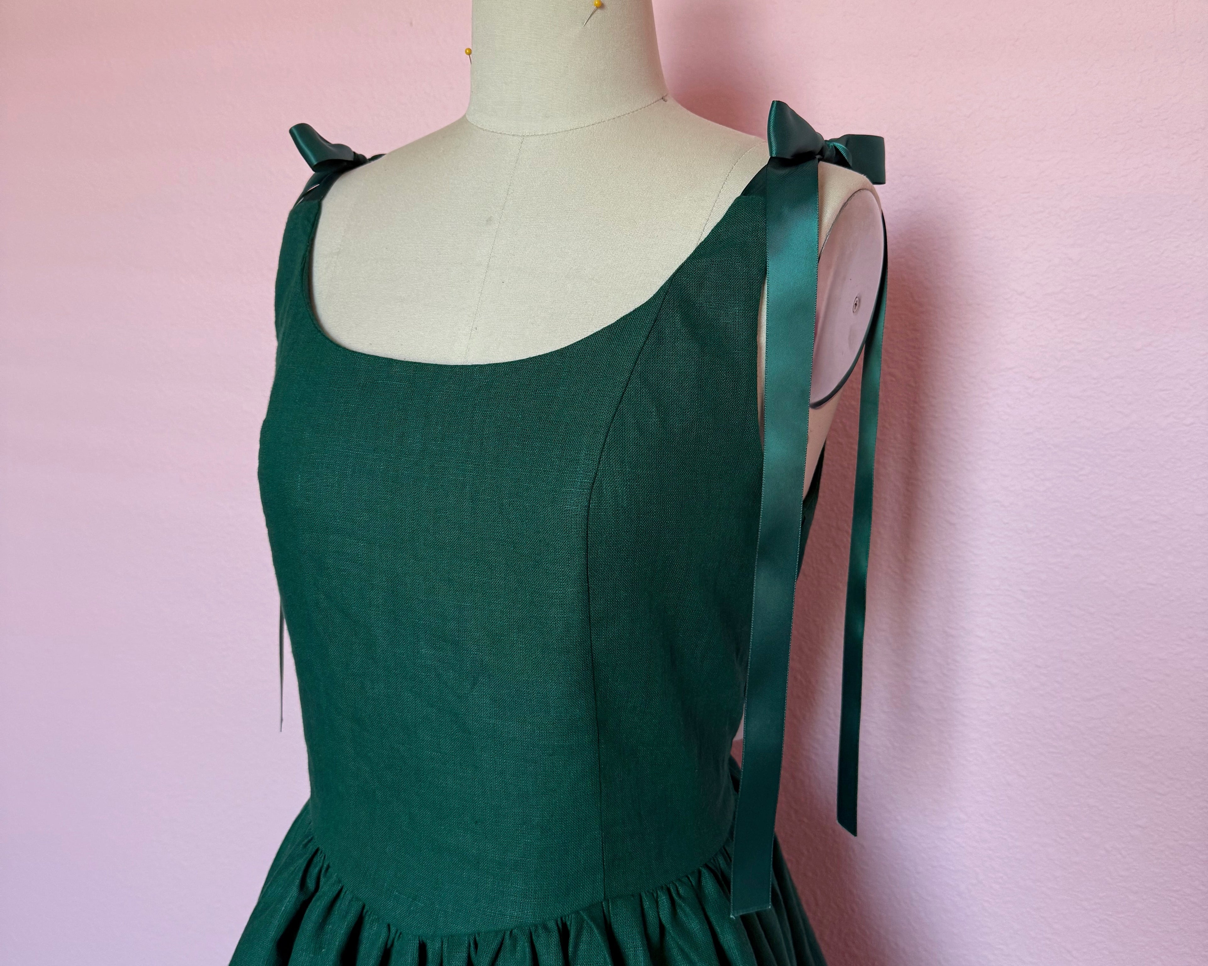 Custom woman's fitted dress made from 100% linen with a scoop neck, gathered skirt, and matching satin ribbon ties at the shoulder.