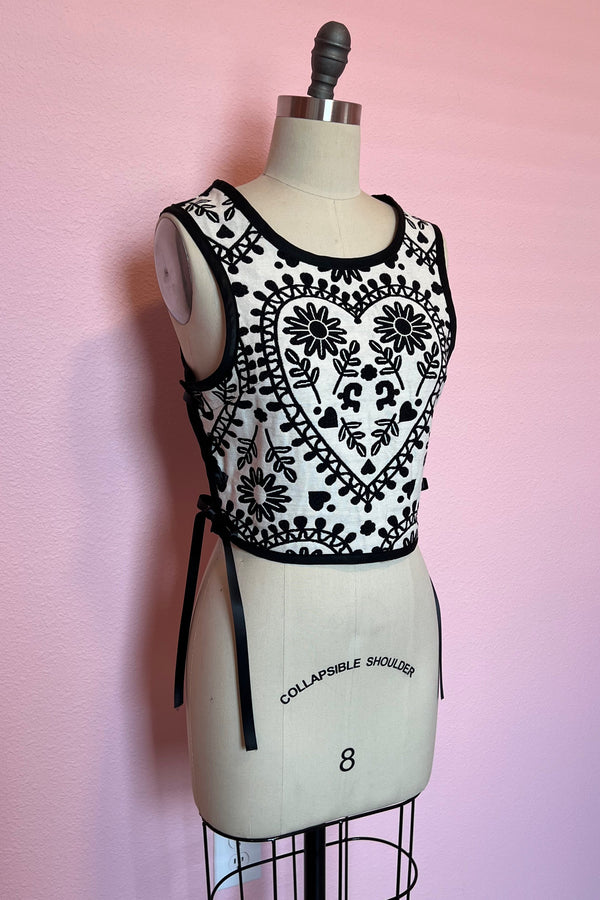 Custom made black and white heart motif sleeveless top with side ribbon corset tie closure on a mannequin against a pink wall.